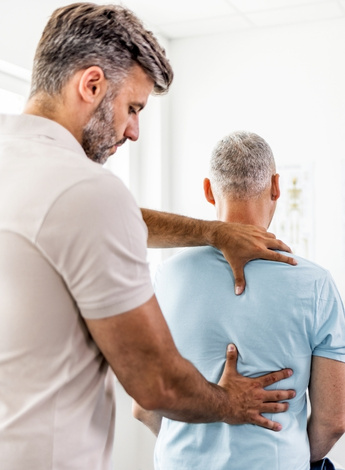 A physiotherapist examines his patient's back